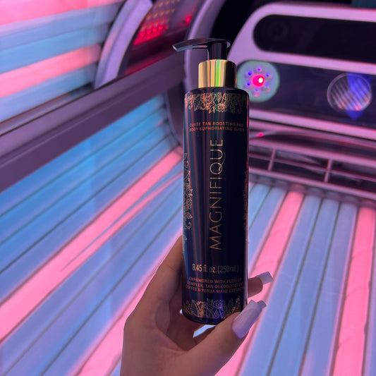 Hand holding Onyx Magnifique cream inside a tanning bed with pink and blue lights
