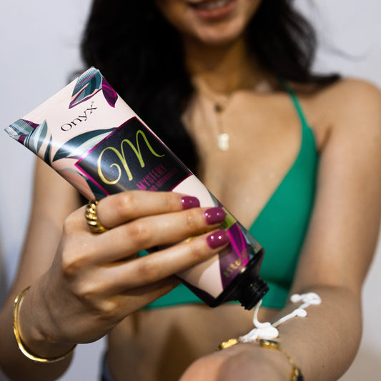 Woman in green bikini applying tanning accelerator cream to arm