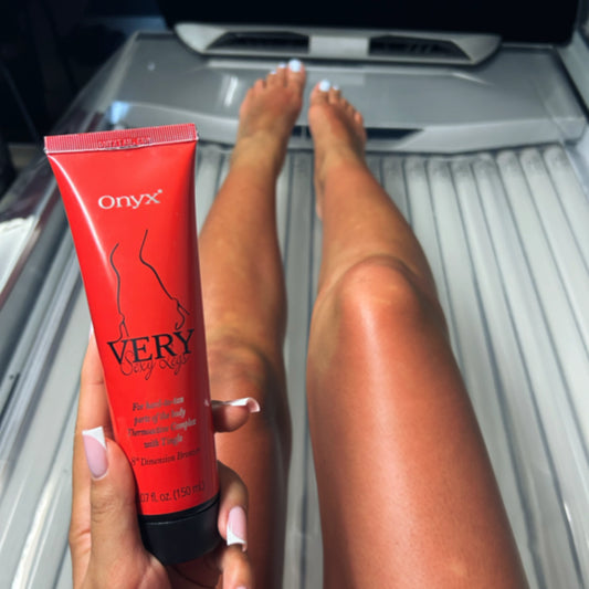 Person lying in a sunbed holding Onyx Very Sexy Legs tingle bronzer cream with tanned legs visible