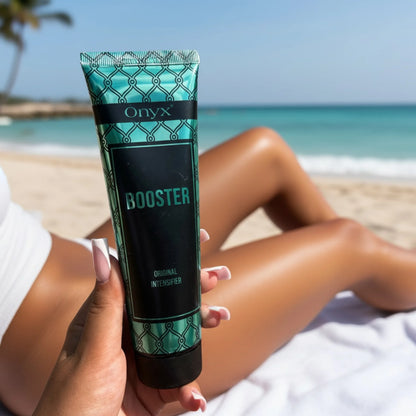 Close-up of an Onyx Booster Original Intensifier tube held on a beach, with the sea and a reclining model in the background.