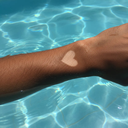 Close-up of an arm near blue pool water with a visible lighter tan mark on the skin.