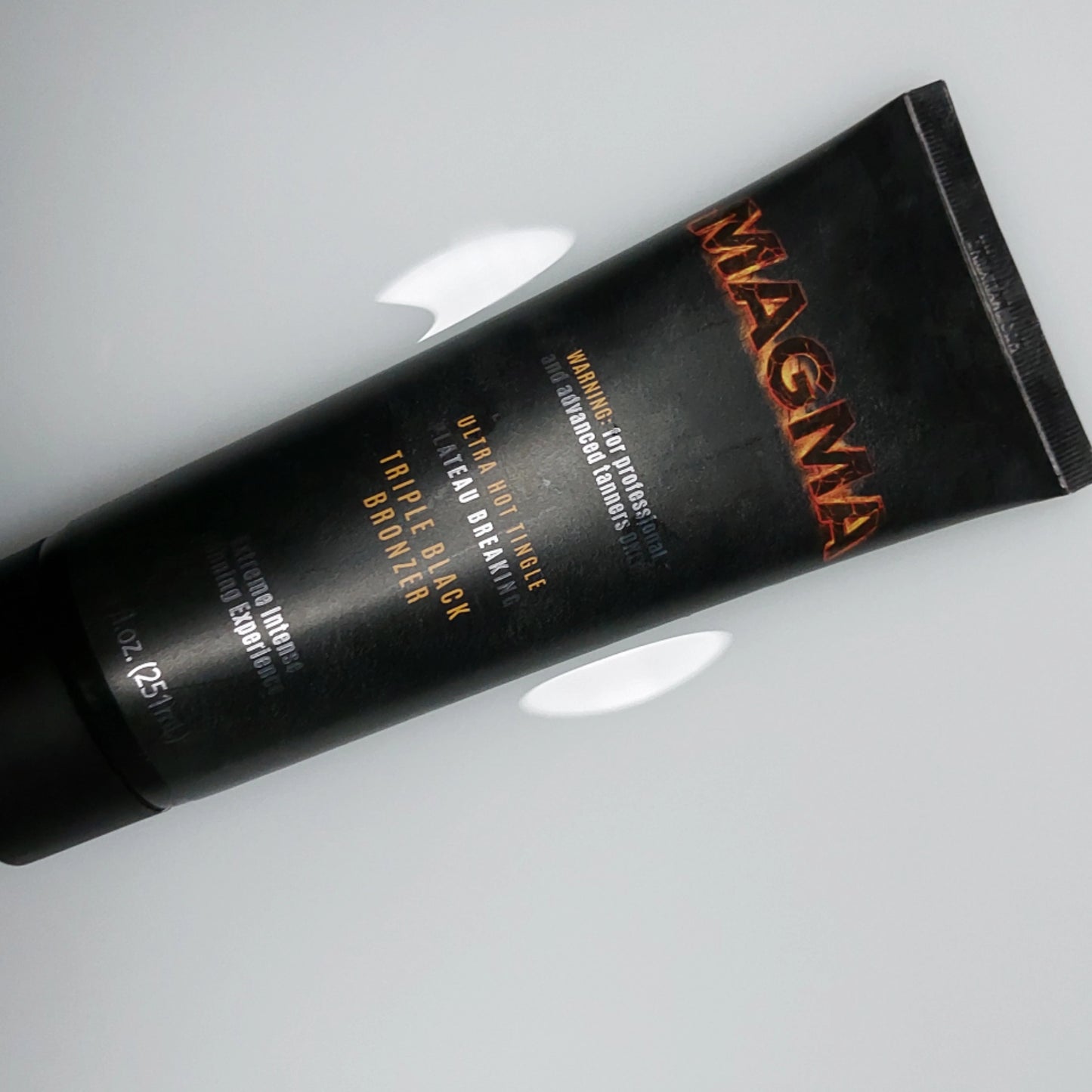 Onyx Magma tingle tanning cream tube placed diagonally on light surface with shadow reflection