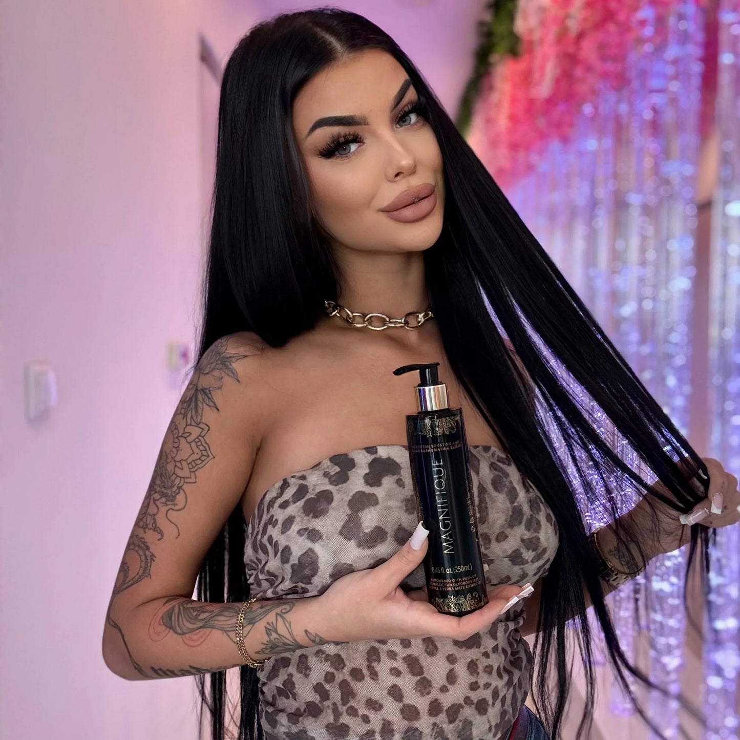 Model holding an Onyx Magnifique tanning lotion bottle cream, with decorative flowers in the background.