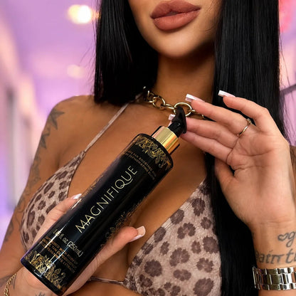 Close-up of a model holding an Onyx Magnifique tanning lotion bottle while wearing a patterned bikini.