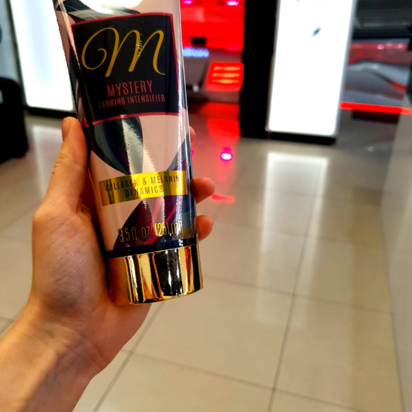 Close-up of Onyx Mystery indoor tanning accelerator cream held in hand at salon