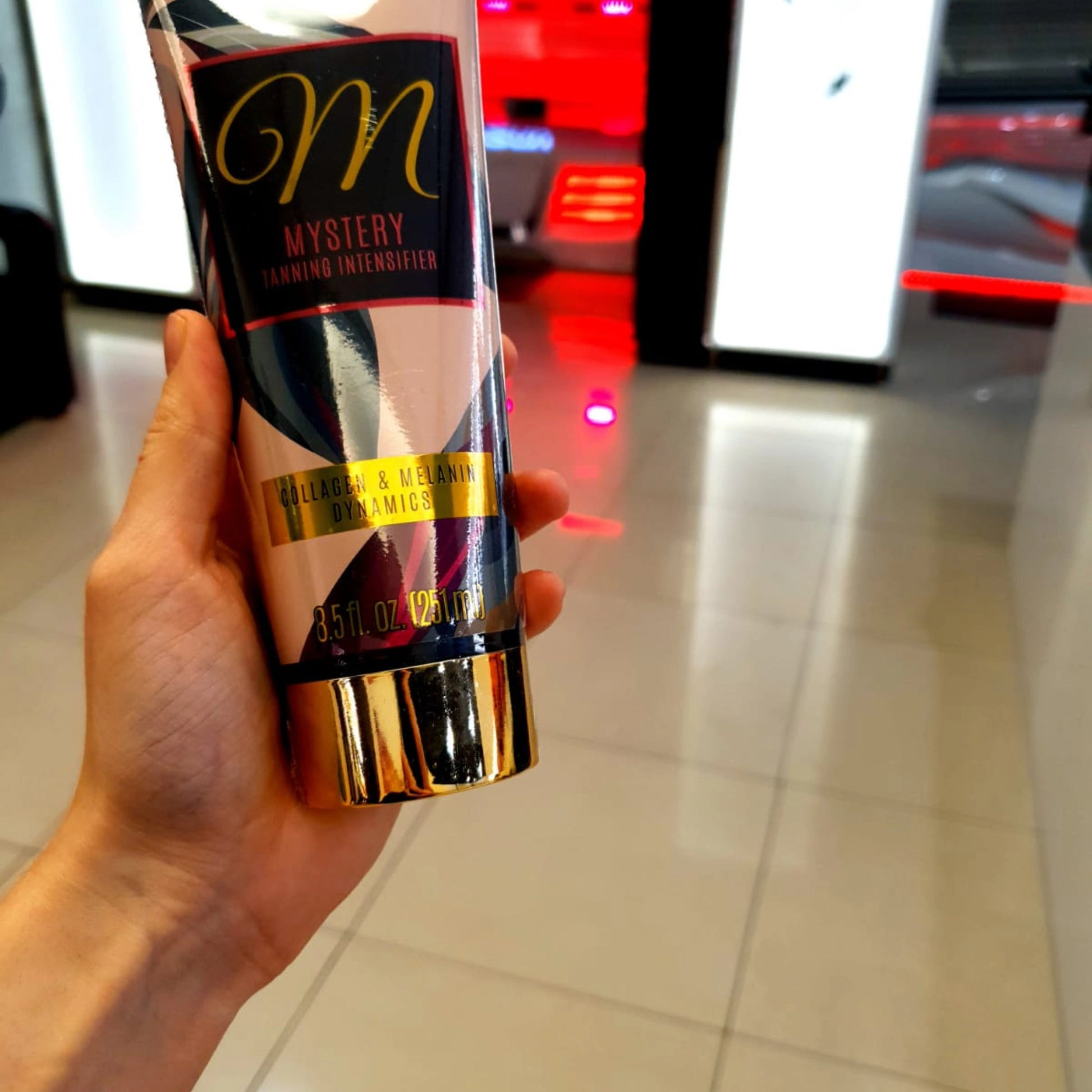 Close-up of Onyx Mystery indoor tanning accelerator cream held in hand at salon