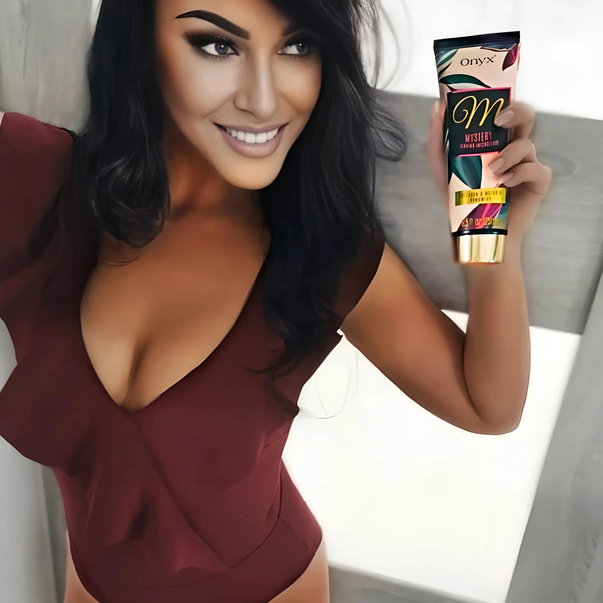 Model in burgundy dress holding Onyx Mystery tanning accelerator cream, smiling