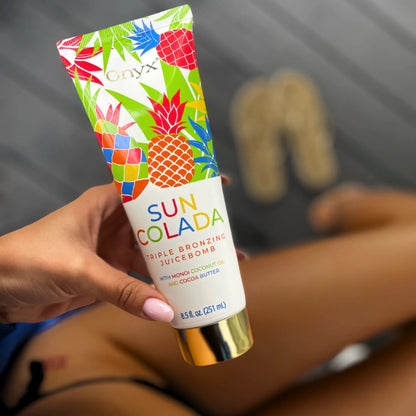 Hand holding Onyx Suncolada sunbed accelerator cream with blurred background