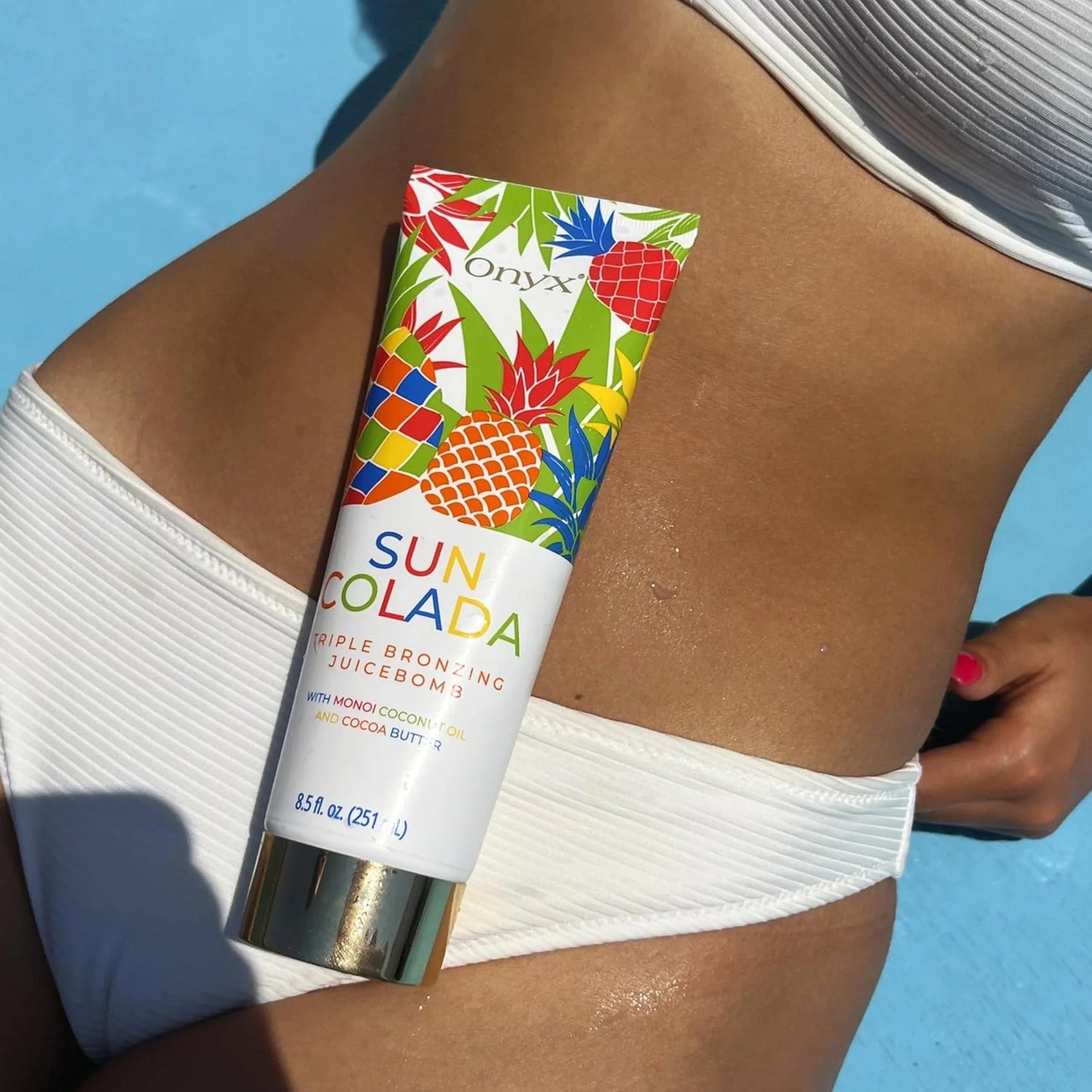 Onyx Suncolada sunbed tanning accelerator applied on tanned stomach with blue background