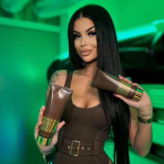 Model holding two Onyx Veneziana bronzer cream products beside a sunbed under green lighting.