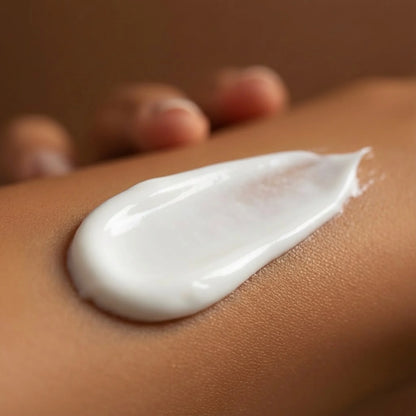A close-up of a white tanning lotion being applied smoothly onto skin, showing its creamy texture.